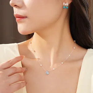 Close-up detail of a minimalist pearl necklace with flower zircon pendant on model