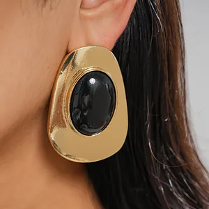 Close-up detail of a vintage gold metal oval earring featuring a central black resin stone