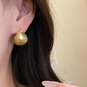 Detailed view of elegant vintage gold brushed half-round earrings worn on a model's ear