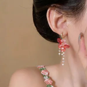 Vista detallada de elegantes pendientes de borla de flores rosas y perlas en la oreja