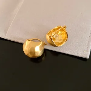 Close-up of vintage brushed gold semi-circle hoop earrings with hammered texture