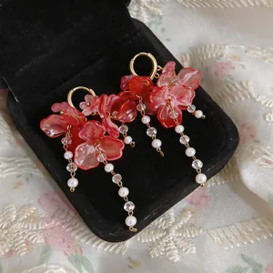 Primer plano de exquisitos pendientes de borla de flores rosas con perlas en un joyero negro