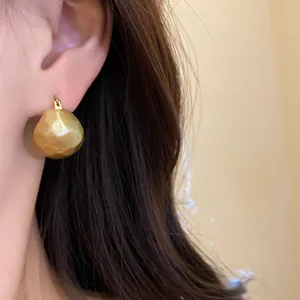 Close-up detail of vintage brushed gold semi-circular earrings worn on a model's ear