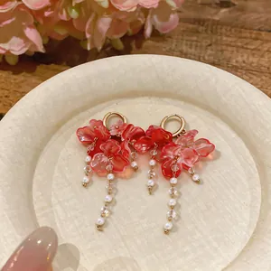 Detalle elegante de pendientes de flores rosas con perlas y cuentas de cristal