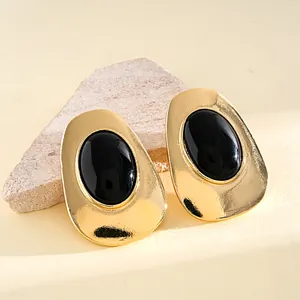 Macro view of vintage gold-tone oval stud earrings with large black resin stones.
