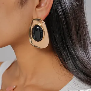 Detail shot of vintage gold geometric stud earrings with black oval resin stone