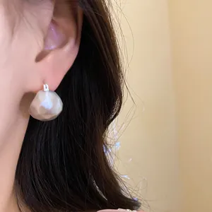 Close-up of brushed silver half-round earrings on ear, showing minimalist texture