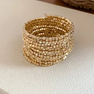 Macro detail of vintage gold multi-layer wrap bracelet with square metallic beads