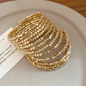 Detail of gold multi-layer wrap bracelet with vintage square beads on a plate.