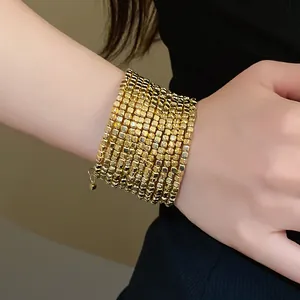 Macro detail of a luxurious multi-layer gold square bead winding bracelet on a wrist