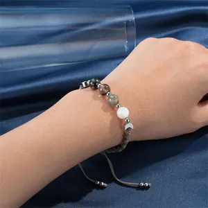 Dettaglio del bracciale curativo intrecciato con perle di pietra di luna e ossidiana.