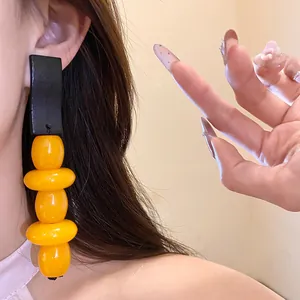 Close-up of vintage yellow resin dangling earrings with black stud worn on ear