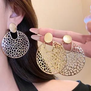 Nahaufnahme minimalistischer, hohlrunder Hängeohrringe in Gold und Silber am Ohr