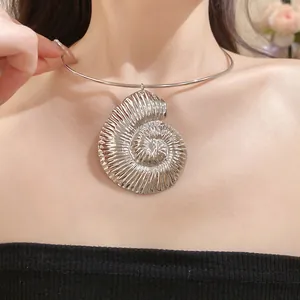 Detail of a large silver metallic ammonite shell pendant worn on a sleek minimalist choker