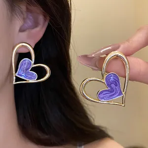 Primer plano de elegantes pendientes de corazón lila con marco dorado en modelo asiática