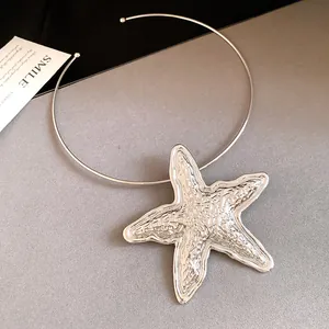 Detailed view of a large metallic silver starfish pendant on a minimalist wire choker necklace.