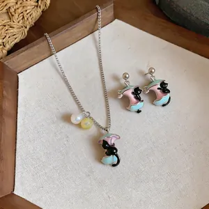 Macro dettagliata di set collana e orecchini con ciondolo a forma di gatto e mela