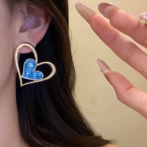 Primer plano detallado de pendientes de esmalte en forma de corazón con marco dorado