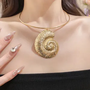 Detailed close-up of a large bohemian gold shell pendant on a thin rigid choker necklace