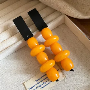 Close-up of vintage orange resin beads and black wood drop earrings in display box