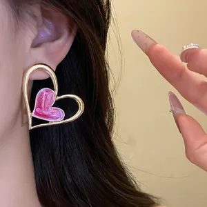 Primer plano detallado de pendientes vintage de corazón en oro con esmalte rosa fino