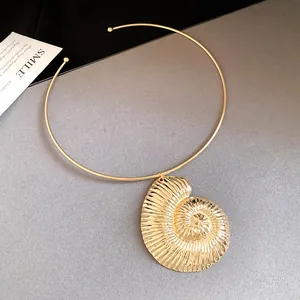 Elegant close-up of a golden nautilus shell pendant on a minimalist rigid choker necklace.