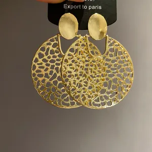 Detailansicht goldener runder Ohrhänger mit Lochmuster für einen eleganten, modernen Stil.