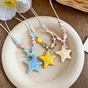 Dettaglio di tre collane colorate con stelle marine in ceramica e perline su un piatto