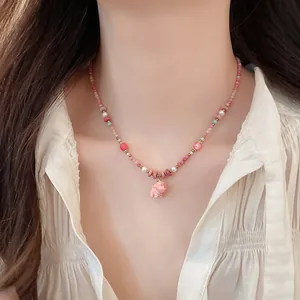 Detail view of a pink ceramic puppy pendant on a dopamine beaded pearl necklace