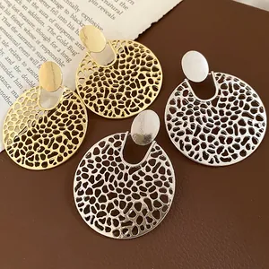 Detailaufnahme eleganter runder Hohlohrringe mit filigranem Muster in Gold und Silber.