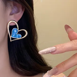 Detalle de pendientes de doble corazón con esmalte azul y acabado dorado en la oreja