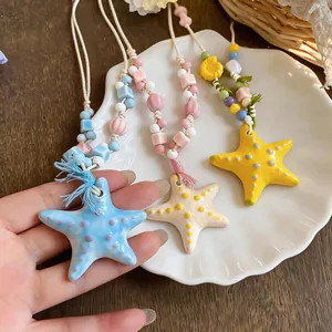 Dettaglio di collane di stelle marine in ceramica con perle colorate e corde intrecciate
