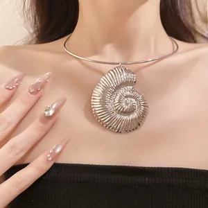 Close-up detail of a silver metallic ammonite shell pendant on a rigid neck collar chain