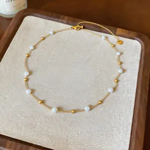 Detaillierte Ansicht einer französischen Perlenkette mit goldenen Perlen auf Stoff.