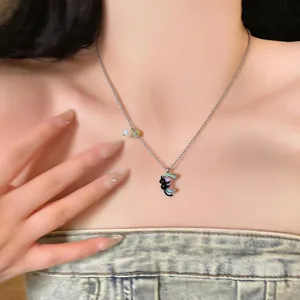 Dettaglio di una collana in argento con ciondolo gatto nero e luna indossata.