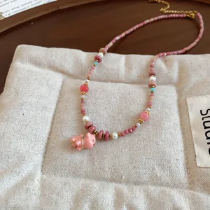 Close-up of pink ceramic puppy pendant on colorful dopamine style beaded necklace