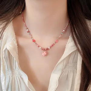 Detailed view of a colorful beaded necklace with a cute pink ceramic puppy pendant.
