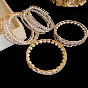 Close-up of multi-layer pearl and rhinestone bracelets in vintage gold and silver tones.