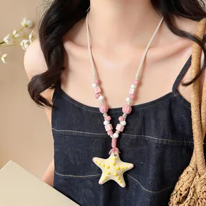 Primo piano di collana di perle in ceramica con ciondolo a stella marina gialla