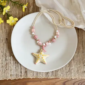 Dettaglio ravvicinato di una collana con stella marina in ceramica e perline rosa e bianche