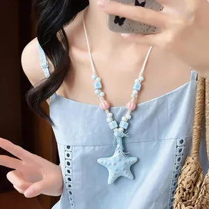 Primo piano di una collana a forma di stella marina in ceramica blu con perline colorate