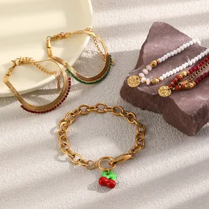 Detailed view of 18K gold plated stainless steel bracelets with cherry and coin charms