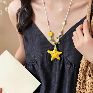 Dettaglio di una collana con pendente a stella marina gialla in ceramica e perline
