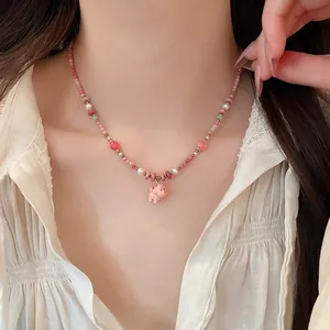 Detailed view of an elegant pink ceramic dog pendant necklace with pearls on neck
