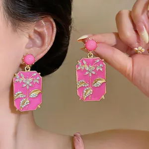 Dettaglio ravvicinato di orecchini vintage rosa quadrati con fiori, foglie e strass