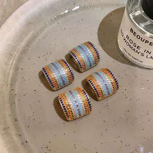 Pendientes de botón cuadrados de lujo con circonitas de colores en plato de cerámica
