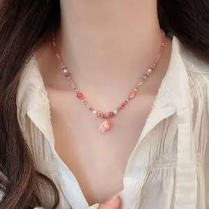 Detailed close-up of a charming pink ceramic dog pendant necklace with pearls on a model
