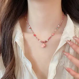 Close-up of a cute pink ceramic puppy pendant on a dainty colorful beaded pearl necklace