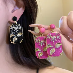 Detailed close-up of vintage enamel rectangle earrings with rhinestone floral design.