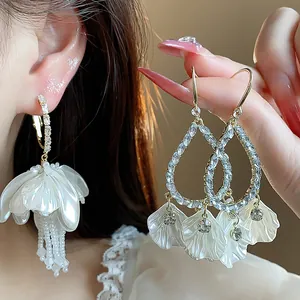 Detailed view of elegant white petal earrings with rhinestone accents and pearl tassels